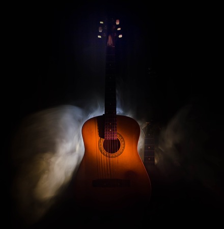 Music concept. Acoustic guitar isolated on a dark background under beam of light with smoke with copy space. Guitar Strings, close up. Selective focus. Fire effects. Surreal guitarの写真素材