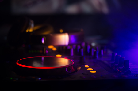 DJ Spinning, Mixing, and Scratching in a Night Club, Hands of dj tweak various track controls on dj's deck, strobe lights and fog, selective focus, close upの写真素材