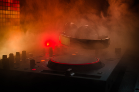 DJ Spinning, Mixing, and Scratching in a Night Club, Hands of dj tweak various track controls on dj's deck, strobe lights and fog, selective focus, close upの写真素材