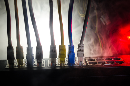 Network switch and ethernet cables, symbol of global communications. Colored network cables on dark...