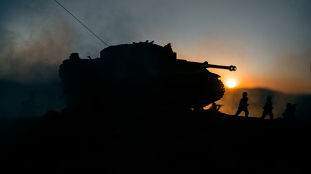 War Concept. Military silhouettes fighting scene on war fog sky background, World War Soldiers Silhouettes Below Cloudy Skyline at sunset. Attack scene. Armored vehicles. German tank in actionの写真素材