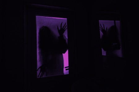 Horror woman in window wood hand hold cage scary scene halloween concept Blurred silhouette of witchの写真素材