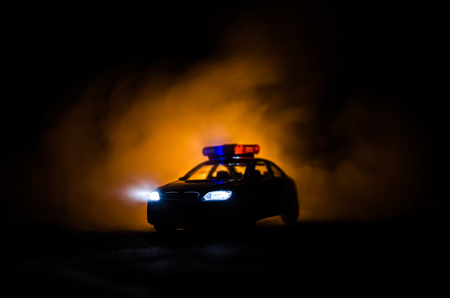 Police car chasing a car at night with fog background. 911 Emergency response police car speeding to scene of crime. Selective focusの写真素材