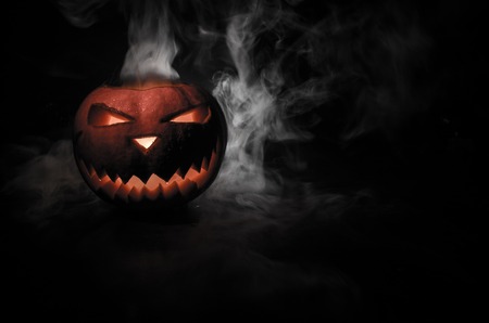 Halloween - old jack-o-lantern on black foggy background. Closeup of scary halloween pumpkinsの写真素材