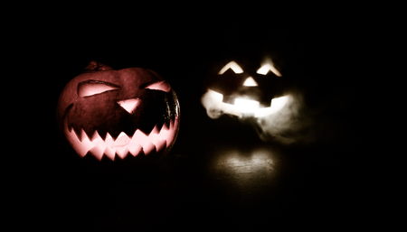 Halloween - old jack-o-lantern on black foggy background. Closeup of scary halloween pumpkinsの写真素材