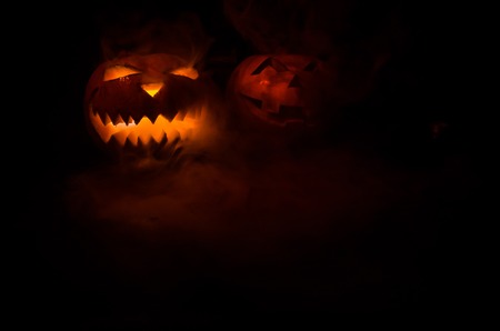 Halloween - old jack-o-lantern on black foggy background. Closeup of scary halloween pumpkinsの写真素材