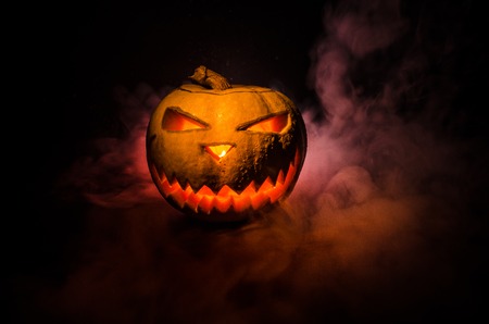 Halloween - old jack-o-lantern on black foggy background. Closeup of scary halloween pumpkinsの写真素材