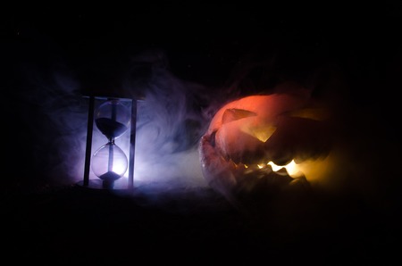 Hourglass. Halloween pumpkin head jack lantern with scary evil faces spooky holiday with burning...