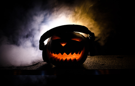Halloween pumpkin on a dj table with headphones on dark background with copy space. Happy Halloween festival decorations and music conceptの写真素材