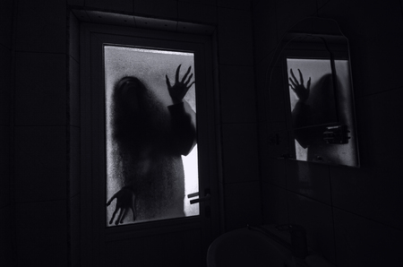 Horror woman in window wood hand hold cage scary scene halloween concept Blurred silhouette of witchの写真素材