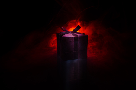 red gift box with red bow on dark toned background. Selective focusの写真素材