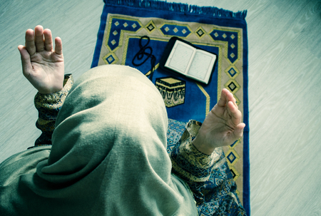 Muslim woman praying for Allah muslim god at room near window.の写真素材