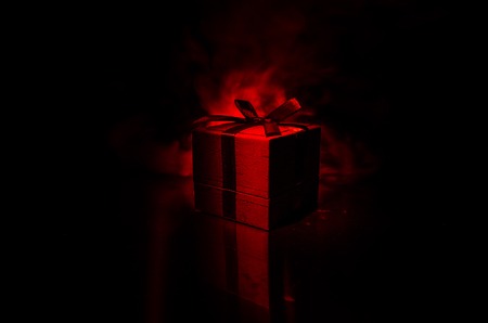 red gift box with red bow on dark toned background. Selective focusの写真素材
