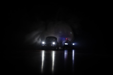 Police car chasing a car at night with fog background. 911 Emergency response police car speeding to scene of crime. Selective focusの写真素材
