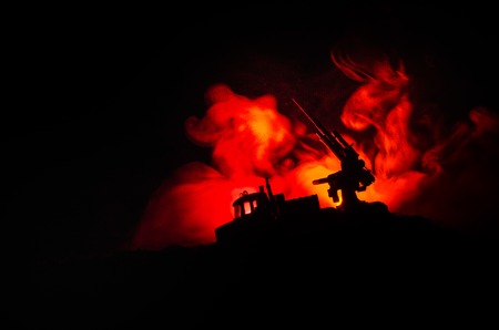 An anti-aircraft cannon and Military silhouettes fighting scene on war fog sky background, World War Soldiers Silhouettes Below Cloudy Skyline at sunset. Attack scene. Armored vehicles.の写真素材