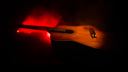Music concept. Acoustic guitar isolated on a dark background under beam of light with smoke with copy space. Guitar Strings, close up. Selective focus. Fire effects. Surreal guitarの写真素材