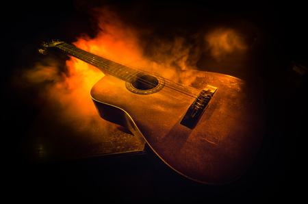 Music concept. Acoustic guitar isolated on a dark background under beam of light with smoke with copy space. Guitar Strings, close up. Selective focus. Fire effects. Surreal guitarの写真素材