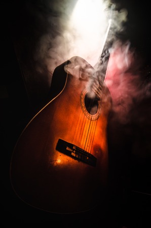 Music concept. Acoustic guitar isolated on a dark background under beam of light with smoke with copy space. Guitar Strings, close up. Selective focus. Fire effects. Surreal guitarの写真素材