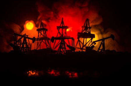 Oil pump oil rig energy industrial machine for petroleum, Group oil rigs and brightly lit industrial site at night. Toned.Background for design. Selective focusの写真素材