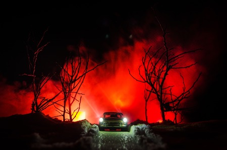 Car lights at nighttime in pine forest with snow. Car lights in winter forest. Toy decorationの写真素材