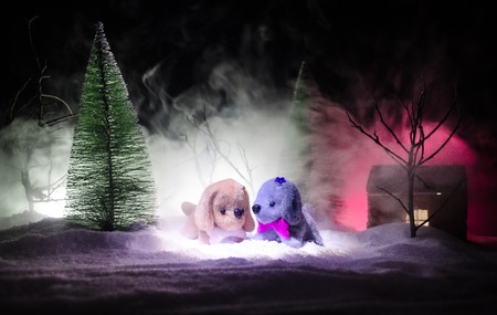 Toy dog - a symbol of the new year under the snow against the background of fir branches. Toy's dog as a symbol of 2018 New Year with a Christmas attributes the new year's inscription. Dark backgroundの写真素材