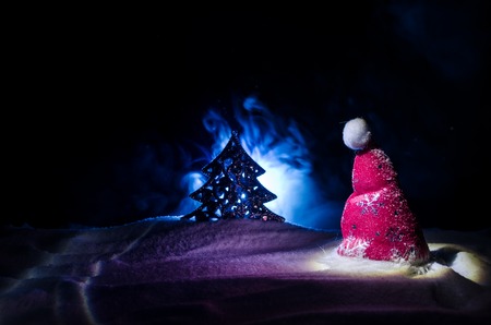Christmas holiday New Year background with Santa Clause hat and blurred Christmas tree on snowy...