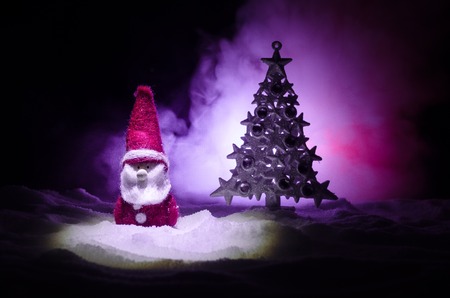 Happy Santa Claus Doll on Christmas time with tree and snow. Colorful bokeh background.