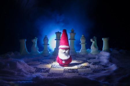Chess in the snow. winter concept. Christmas or New Year present on a chessboard with Santa Claus on a dark background. Copy space. Selective focusの写真素材