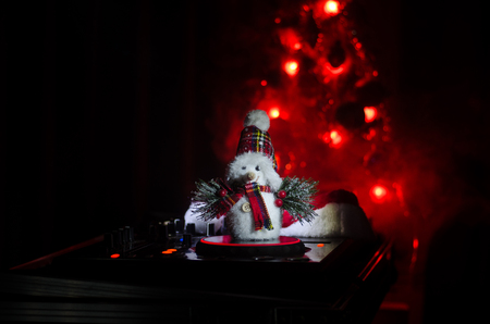 Dj mixer with headphones on dark nightclub background with Christmas tree New Year Eve. Close up...