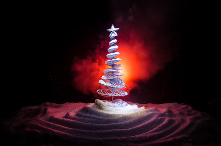 Christmas background with snowy fir tree. Snow Covered Christmas Tree stands out brightly against the dark red tones of this snow covered scene. Toned dark background decorationの写真素材