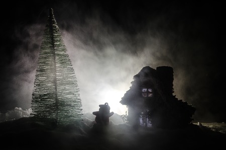 Happy Santa Claus Doll on Christmas time with tree and snow. Colorful bokeh background. Santa Clause and Merry Christmas model figure toy on dark toned foggy backgroundの写真素材