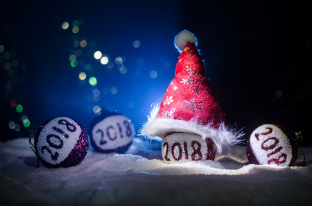 Red christmas balls with 2018 number and Santa Clause hat on natural snow background .Happy new year 2018 concept.Copy space.Selective focus. Dark Foggy backgroundの写真素材