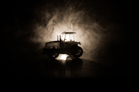 Silhouette of tractor at night with dark foggy background. Toned. Burning vehicle. Decorationの写真素材