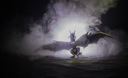 Silhouette of fire breathing dragon with big wings on a dark orange backgroundの写真素材