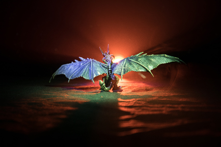 Silhouette of fire breathing dragon with big wings on a dark orange backgroundの写真素材