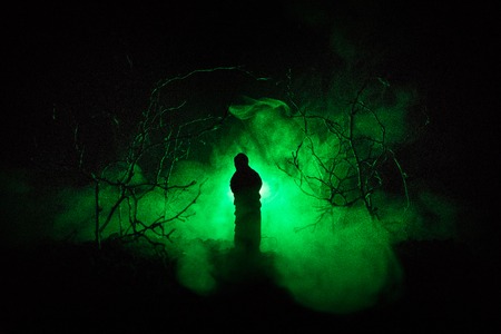Alone girl with the light in the forest at night, or blue toned night forest at the fog time