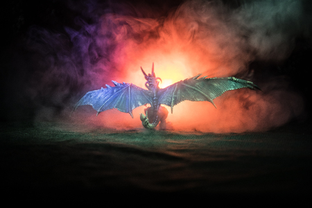 Silhouette of fire breathing dragon with big wings on a dark orange backgroundの写真素材