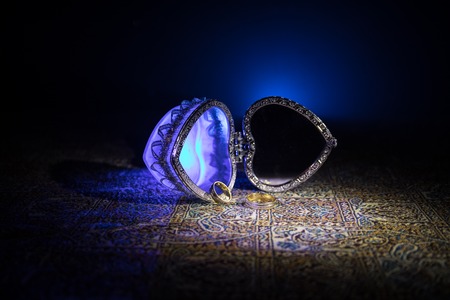 Opened old vintage silver heart-shaped casket for wedding rings on dark toned smoky light background. Valentine love concept. Selective focusの写真素材