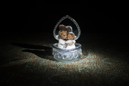 Love concepts of wedding teddy bear in silver heart gift box on table for valentines day and wedding. Dark smoky toned background. Selective focusの写真素材