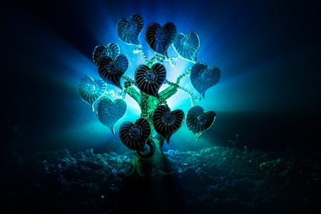 Abstract field with tree and hearts on it behind dark foggy toned sky. Love tree of dreams. Valentine concept background. Selective focusの写真素材