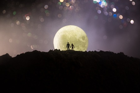Amazing love scene. Silhouettes of young romantic couple standing under the moon light. Valentine`s day conceptの写真素材