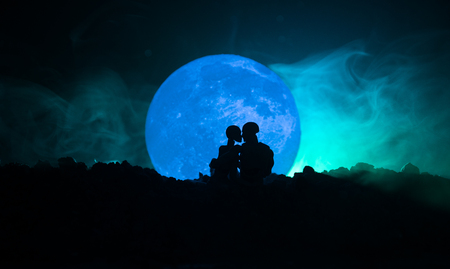 Silhouette of couple kissing under full moon. Guy kiss girl hand on full moon silhouette background. Valentine`s day decor concept. Silhouette of loving couple kissing against the full moonの写真素材