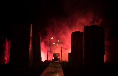 Empty street of burnt up city, flames on the ground and blasts with smoke in the distance. Apocalyptic view of city downtown as disaster film poster concept. Night scene. City destroyed by war.の写真素材