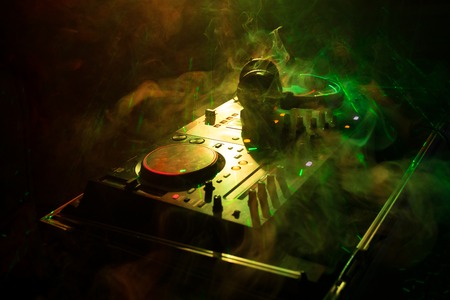 DJ Spinning, Mixing, and Scratching in a Night Club, Hands of dj tweak various track controls on dj's deck, strobe lights and fog, or Dj mixes the track in the nightclub at party. Selective focusの写真素材