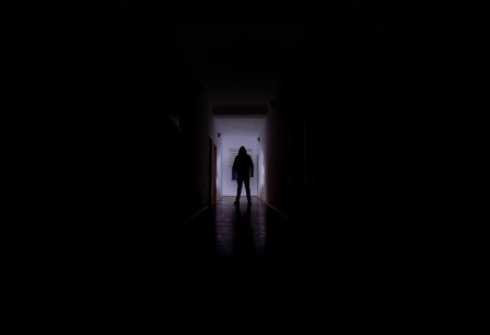 Dark corridor with cabinet doors and lights with silhouette of spooky horror man standing with different poses. Halloween conceptの写真素材