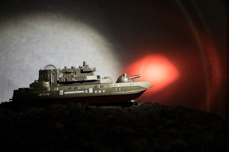 Sea battle scene. Silhouette of military war ship on dark foggy toned sky background. Selective focusの写真素材