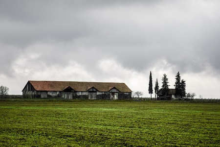 Beautiful landscape of mountains and forest with village building or old abandoned ruined brick house. Foggy forest and old building or old wooden hut cabin in mountain alps at rural fall landscapeの写真素材