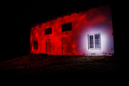 Old house with a Ghost in the forest at night or Abandoned Haunted Horror House in fog. Old mystic building in dead tree forest. Creepy house in the middle of a dark forest. Surreal lightsの写真素材