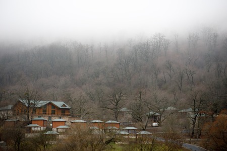 Beautiful landscape of mountains and forest with village building or old abandoned ruined brick house. Foggy forest and old building or old wooden hut cabin in mountain alps at rural fall landscapeの写真素材