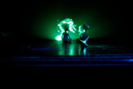 Totem spinning top spinning, wobbling and stopping. Spinning top on mirror surface with toned smoke background light. Whirligig in action in dark room on table. Selective focusの写真素材